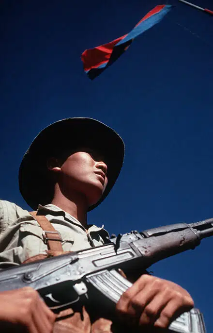 Un soldat vietcong siégeant sous le drapeau de son mouvement (le Viêt-Cong, nom du mouvement de résistance et de libération nationale « intérieur » du Sud Viêt Nam)